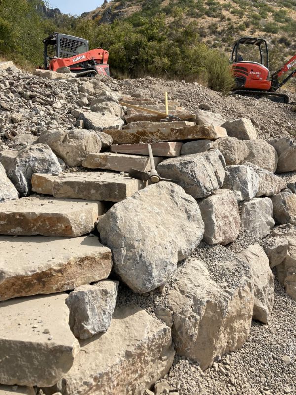 Two excavators at the top of a rocky hill